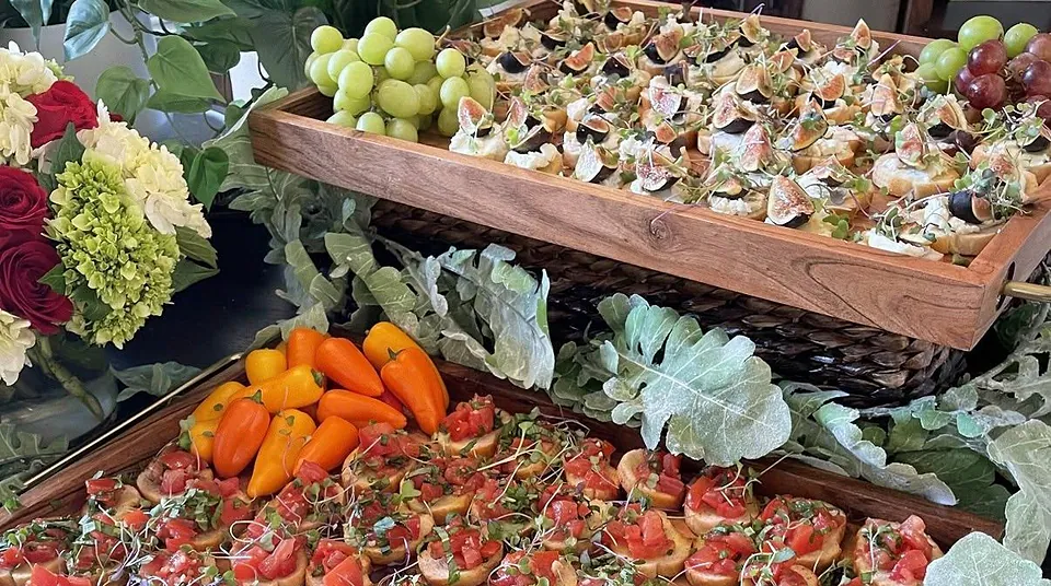 Buffet mit Bruschetta-Platten, Feigen-Häppchen auf einer Etagere, Trauben und Blumenschmuck